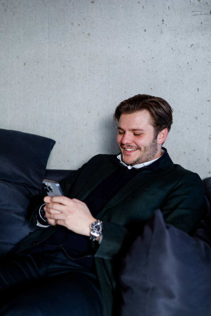 Mann smiler mens han ser på telefonen