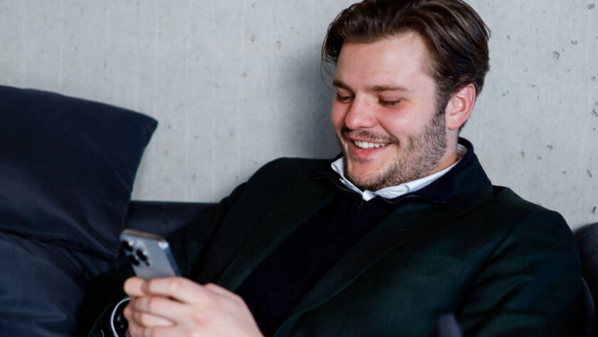 Mann smiler mens han ser på telefonen